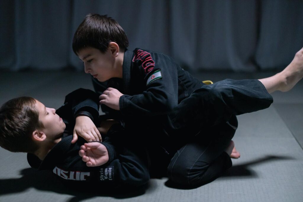 Children engage in jiu jitsu sparring session wearing gis indoors. Martial arts training and practice.